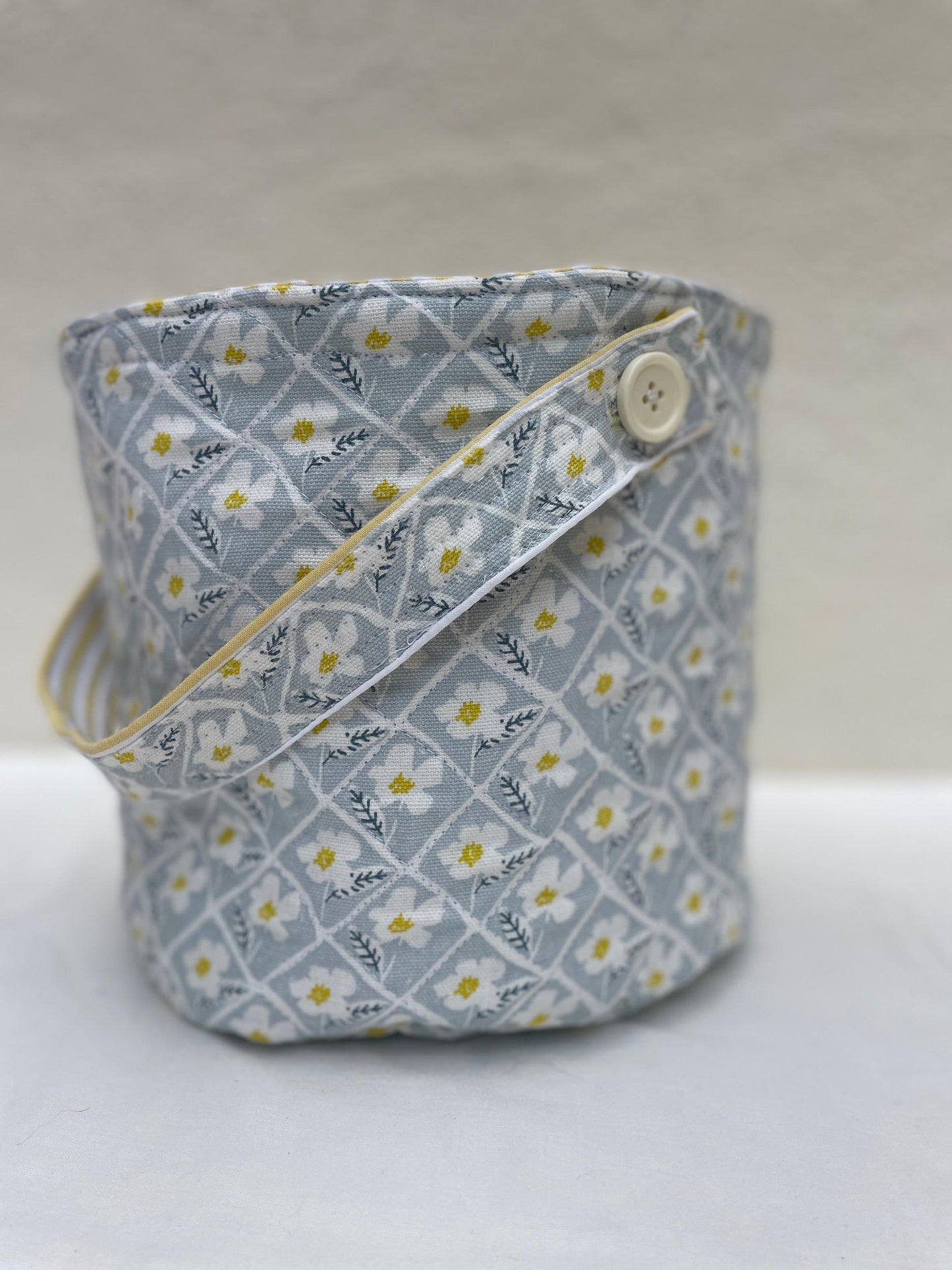 Fabric basket with floral pattern and button on a white background