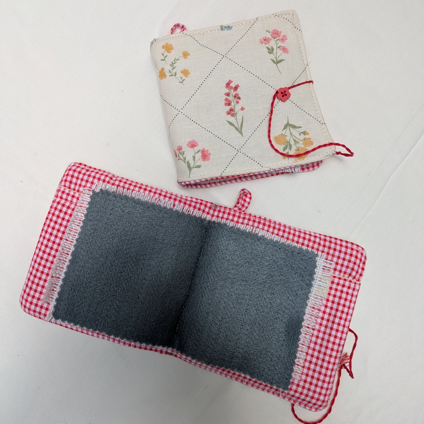 Two fabric needle books on a white background, one with a floral pattern and the other with a checkered pattern.