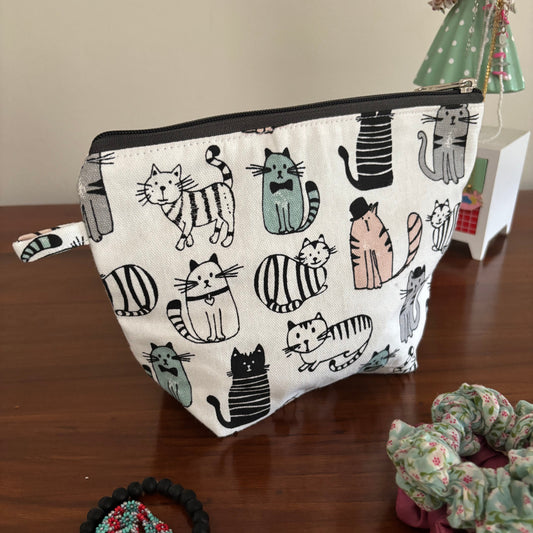 Small pouch with cat pattern on a wooden surface with hair ties.