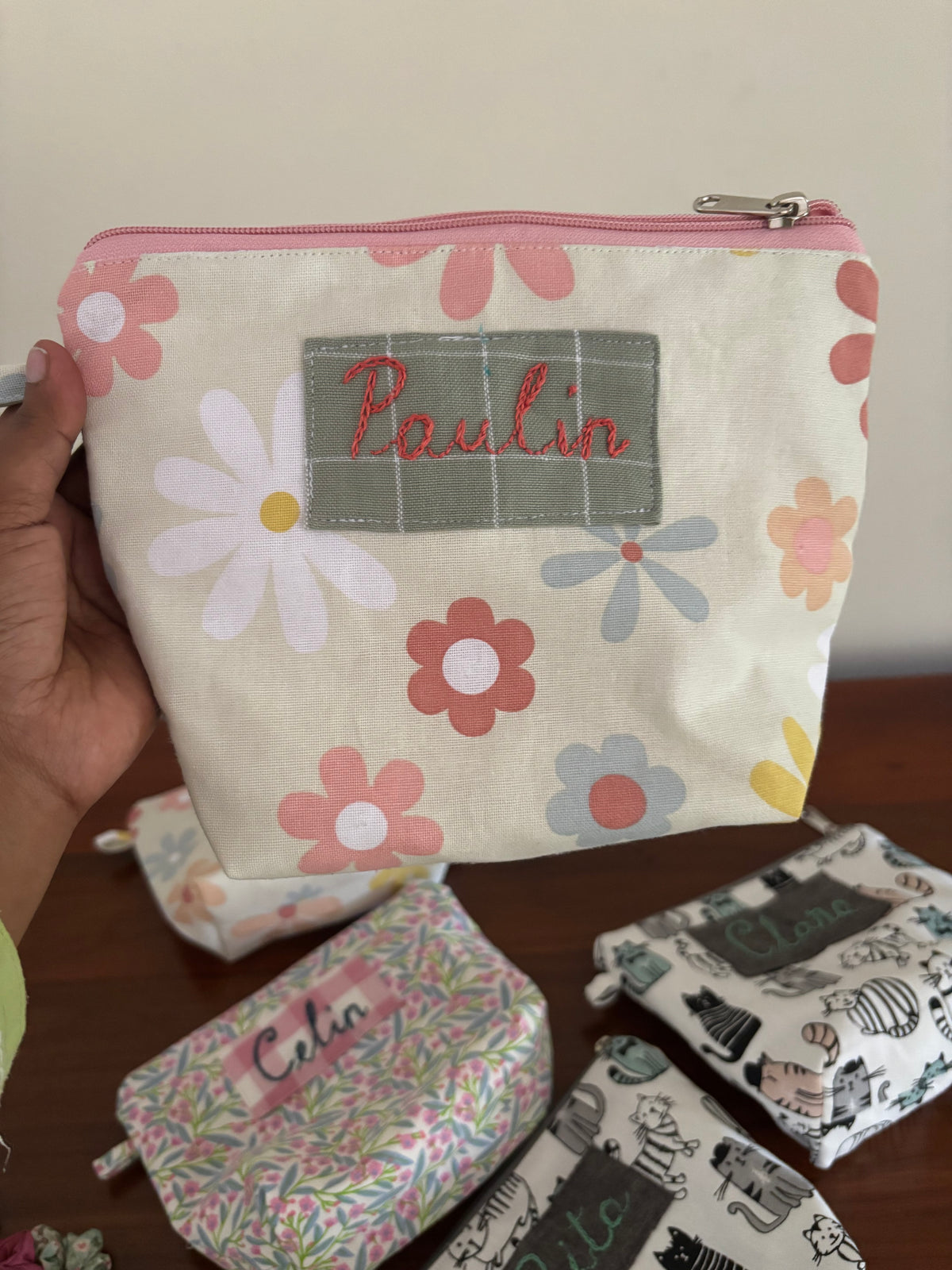 Floral-patterned pouch with 'Balin' label held by a hand, with more pouches in the background.