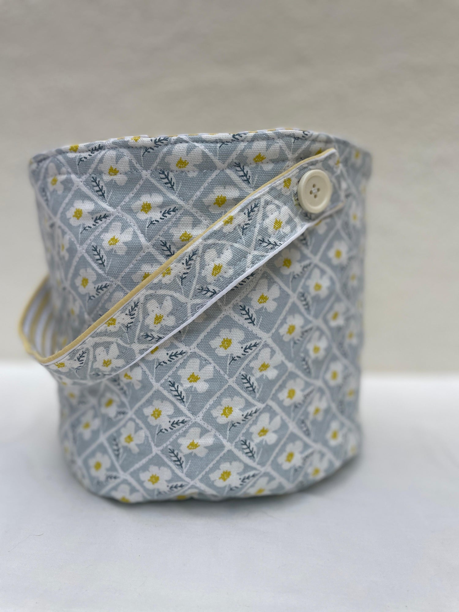Fabric basket with floral pattern and button on a white background