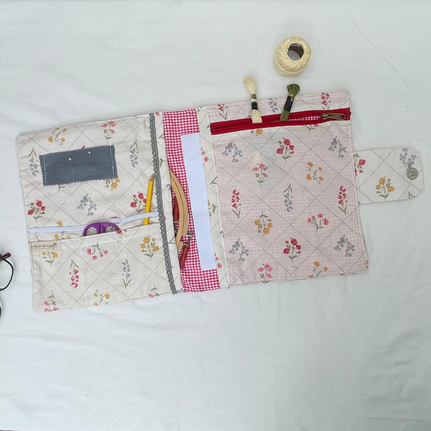 A sewing folder packed with a;; sewing tools inclusing sciccors, threads pencil and pins