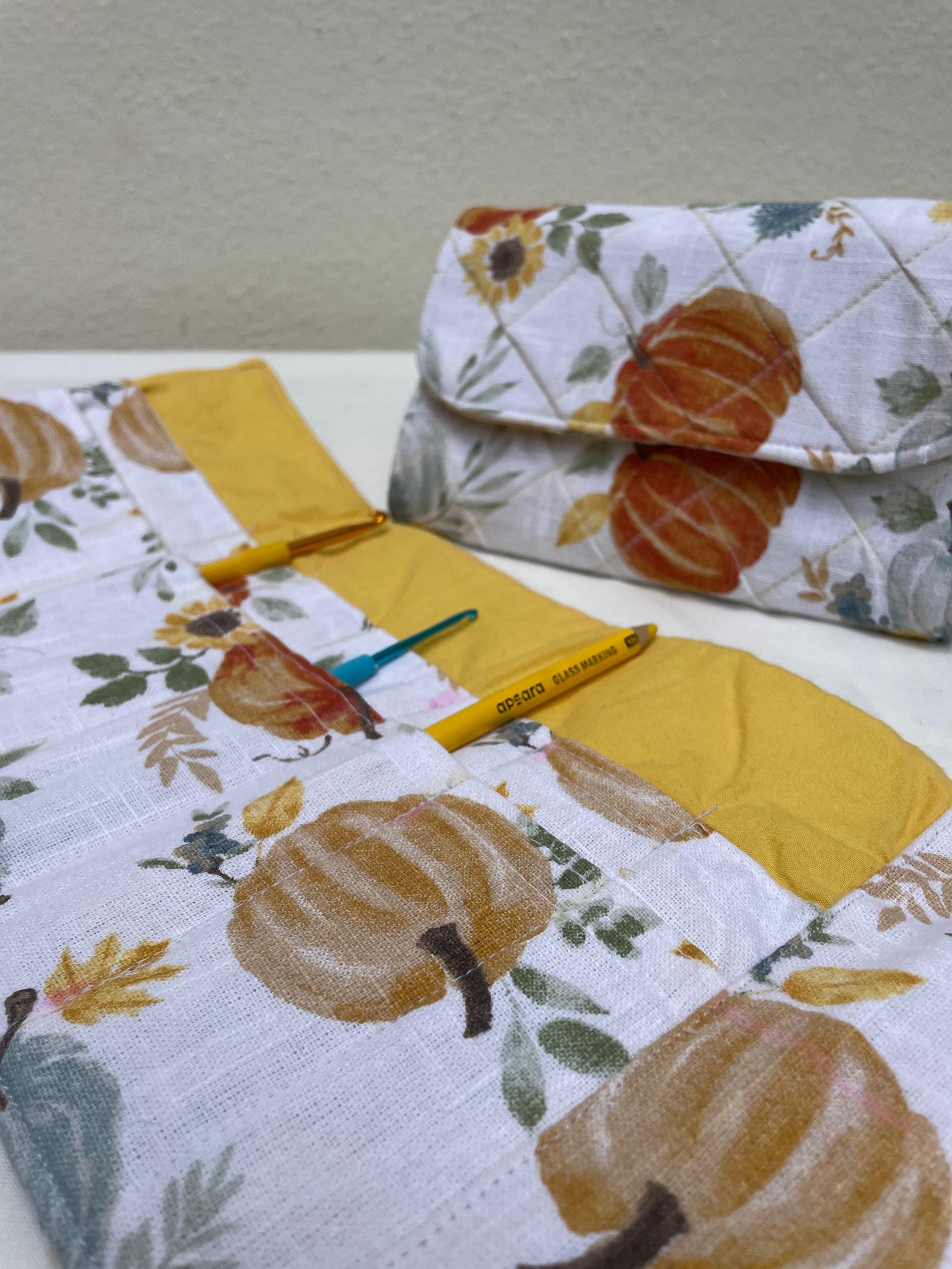 Floral and pumpkin-patterned fabric with a yellow pen on a white surface