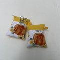 Two fabric pincushions with pumpkin designs on a white surface.