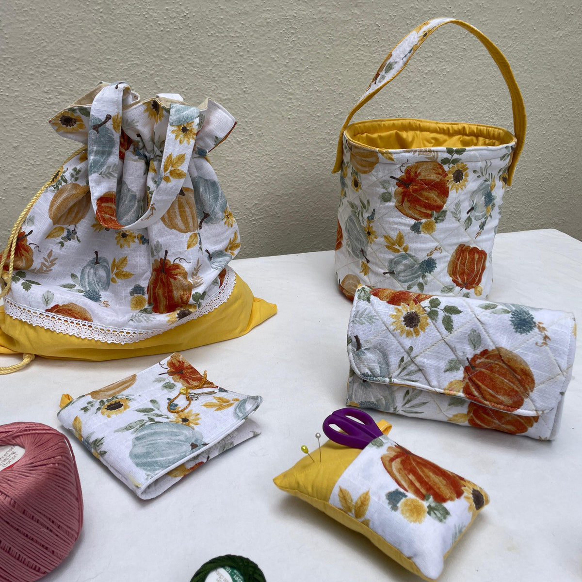 Collection of fabric bags and pouches with autumn-themed designs on a white surface.