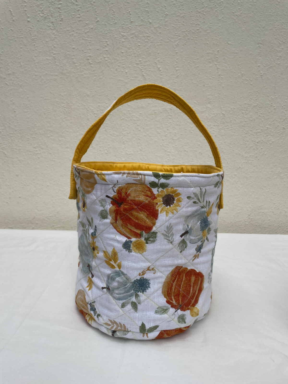 Fabric basket with pumpkins and sunflowers on a white surface