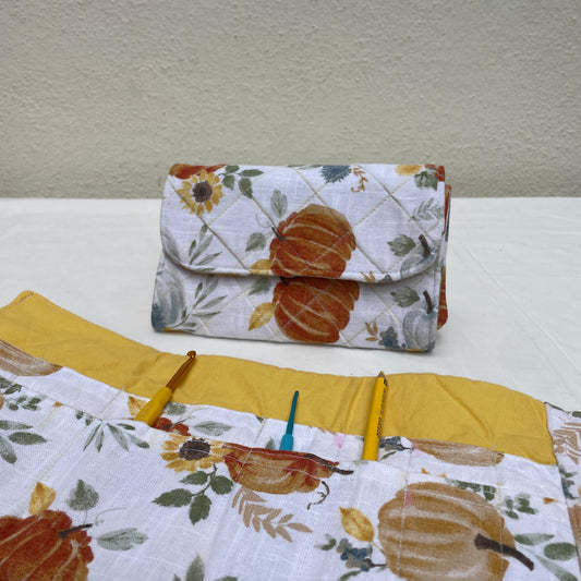 Two quilted crochet hook rolls with autumn-themed designs on a white surface.