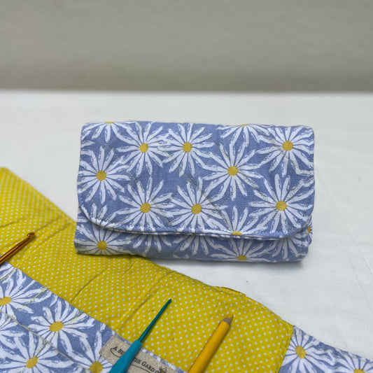 Fabric crochet hook roll with floral pattern and crochet tools on a white surface