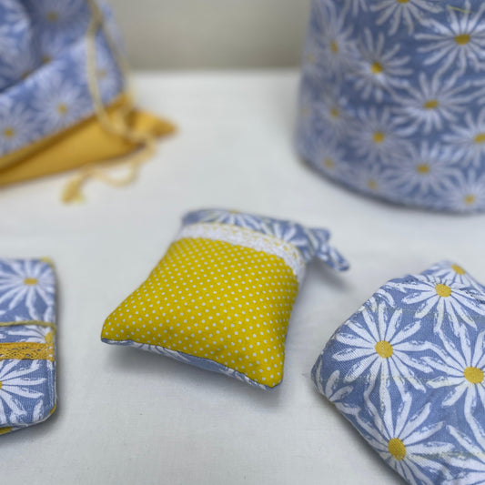 Fabric pincushion with floral and polka dot patterns on a white surface