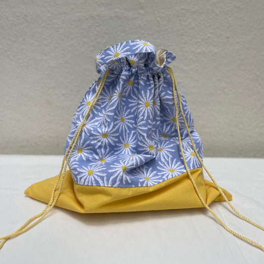 Drawstring bag with blue floral pattern and yellow drawstrings on a neutral background