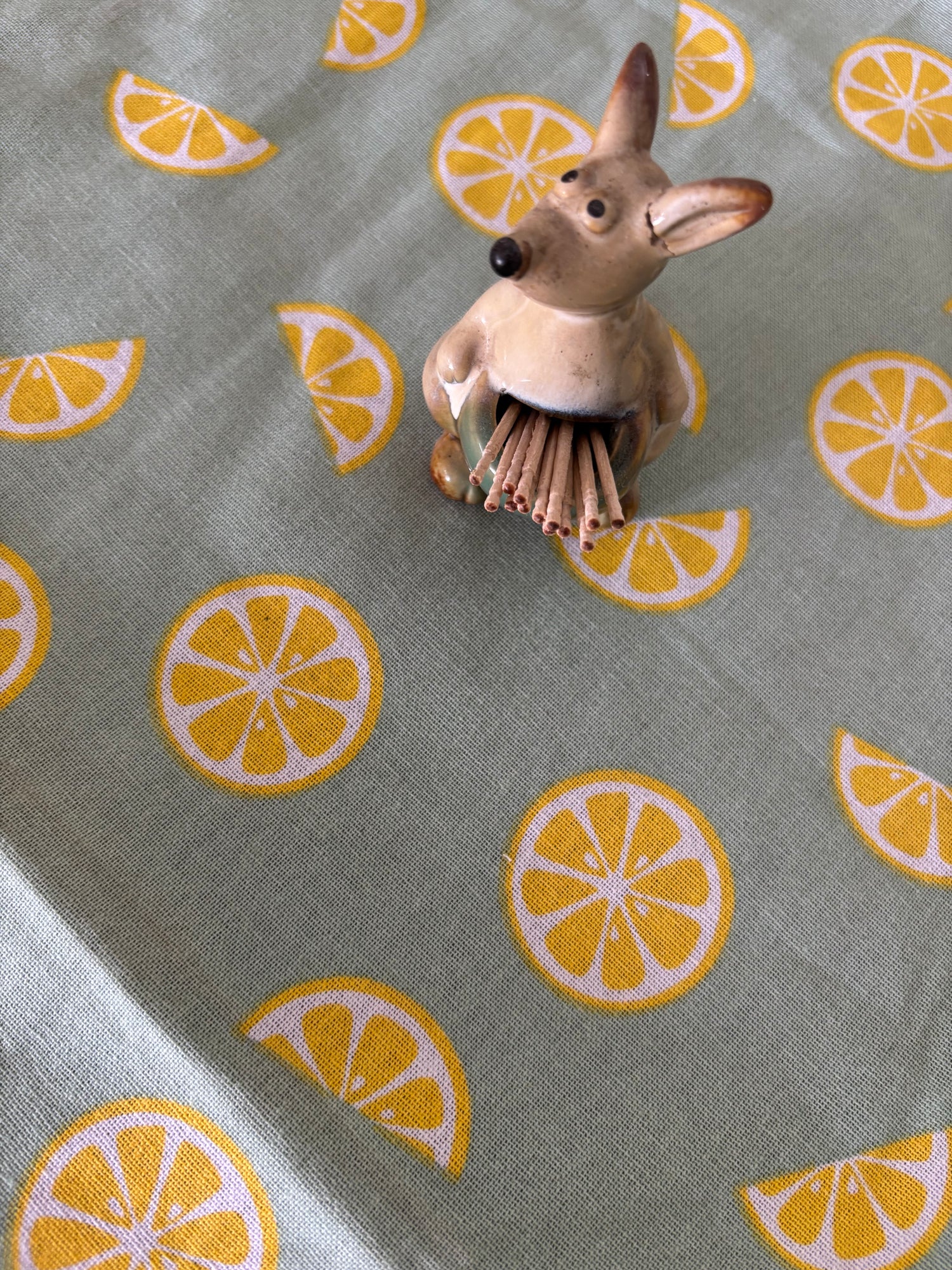 Small figurine of a deer on a fabric with lemon pattern