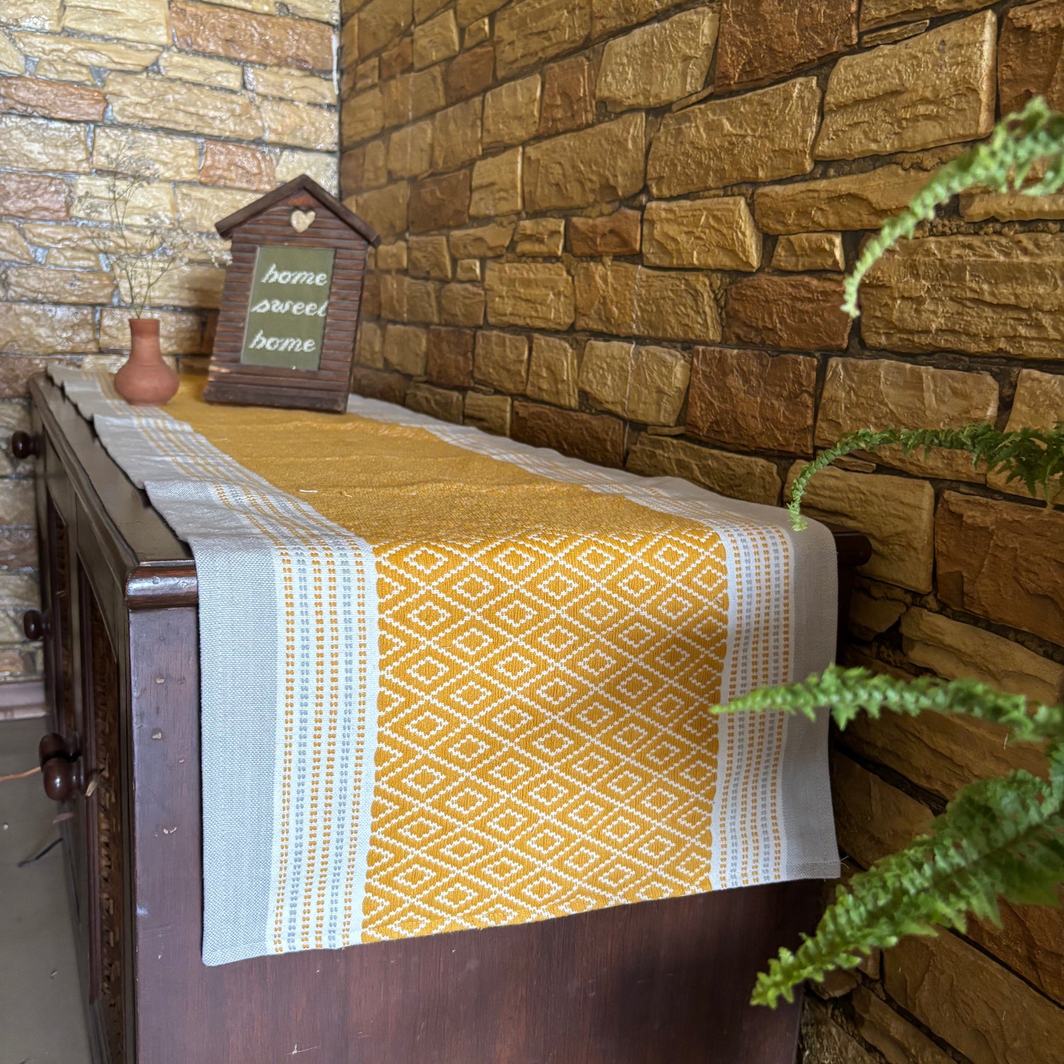 Table with a patterned tablerunneragainst a stone wall