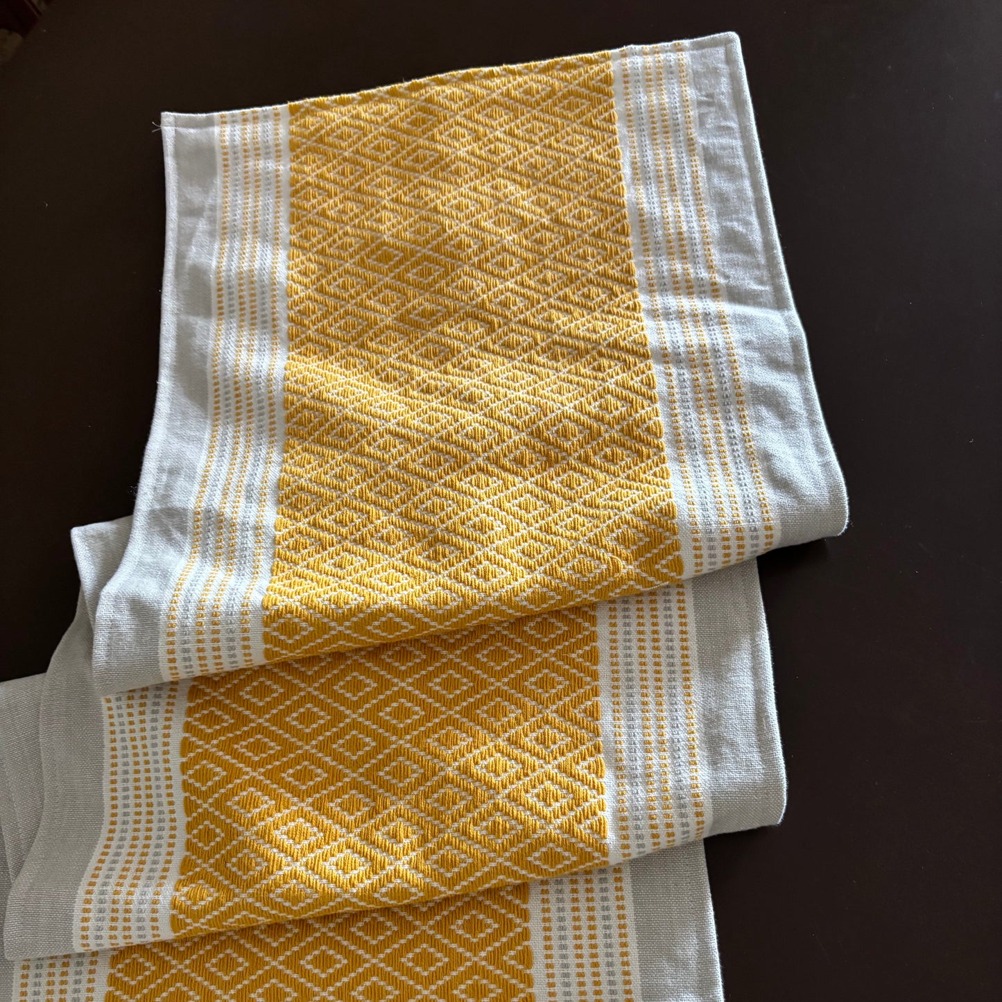 Three yellow and white patterned towels on a dark surface
