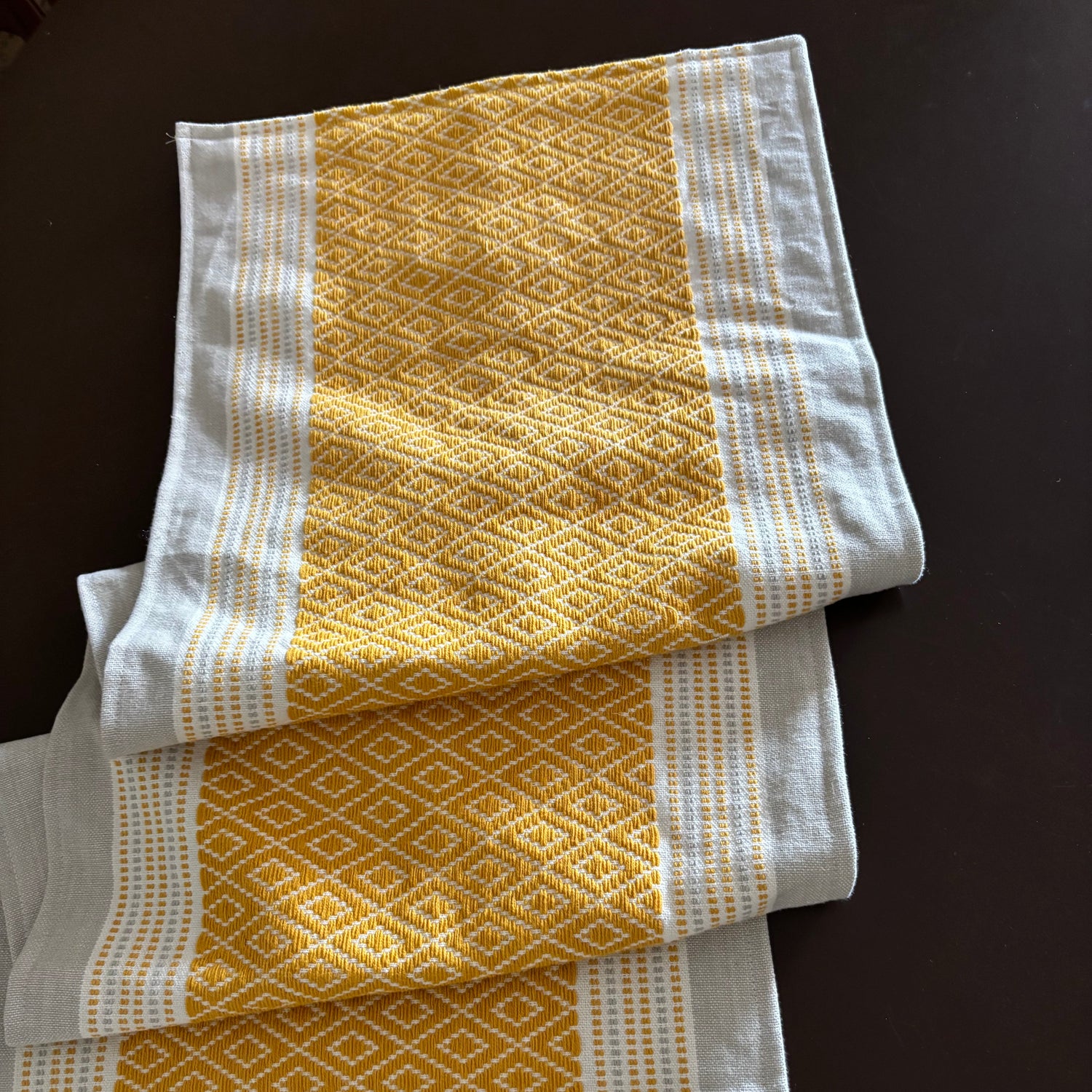 Three yellow and white patterned towels on a dark surface
