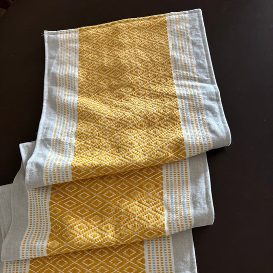 Three yellow and white patterned towels on a dark surface