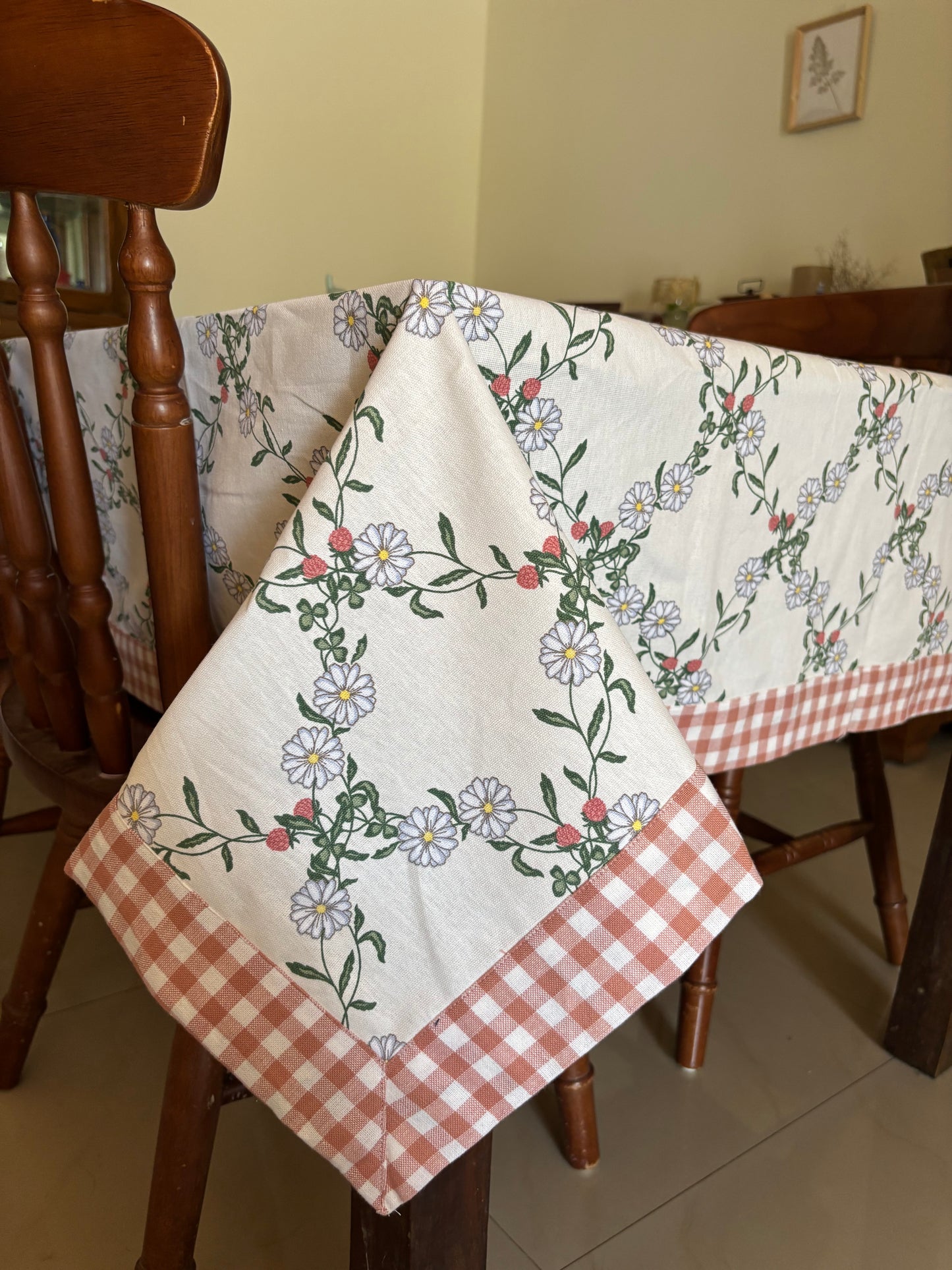 Floral and checkered tablecloth draped over a wooden table