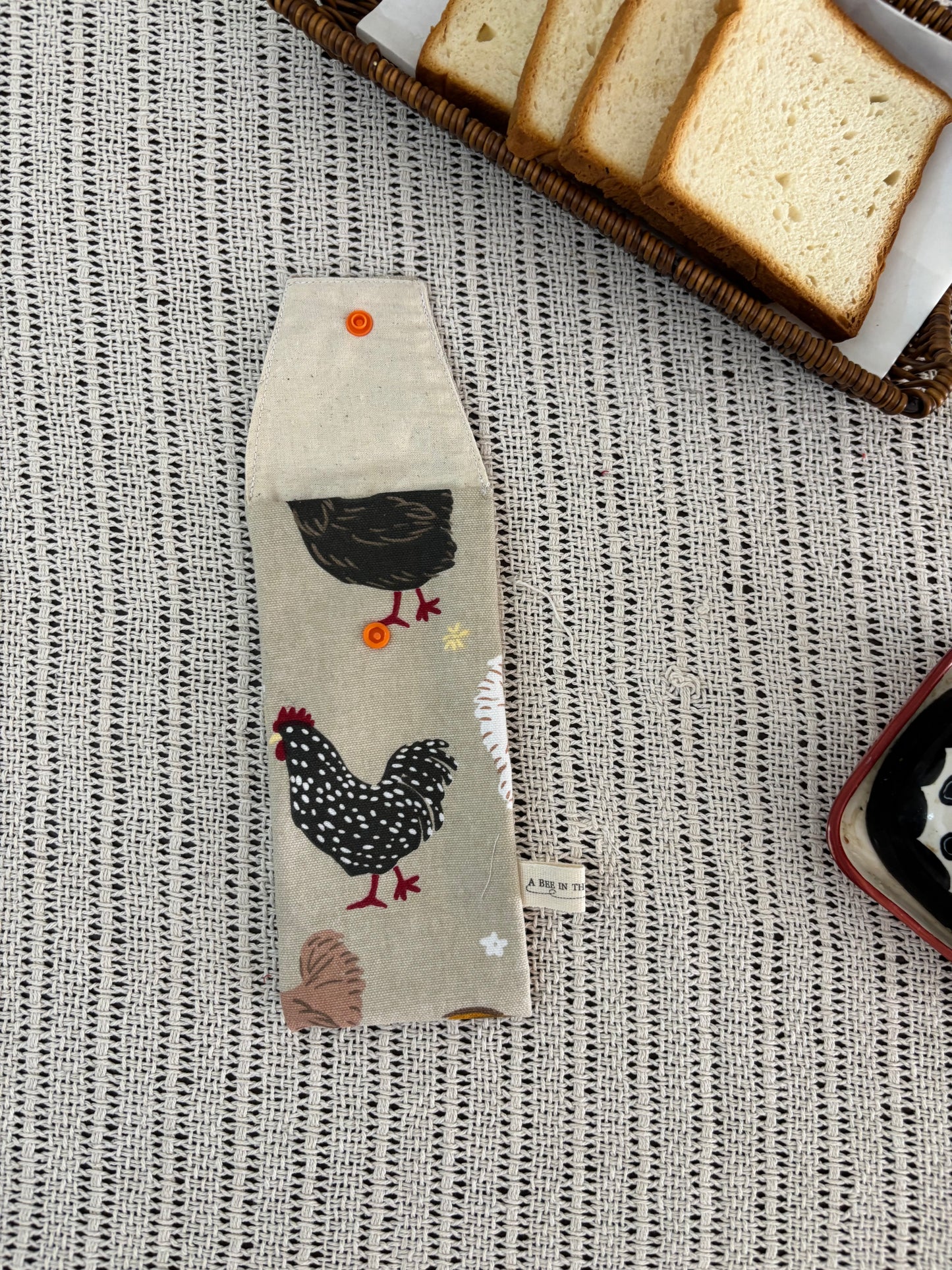 Fabric with chicken design on a textured surface with bread slices.