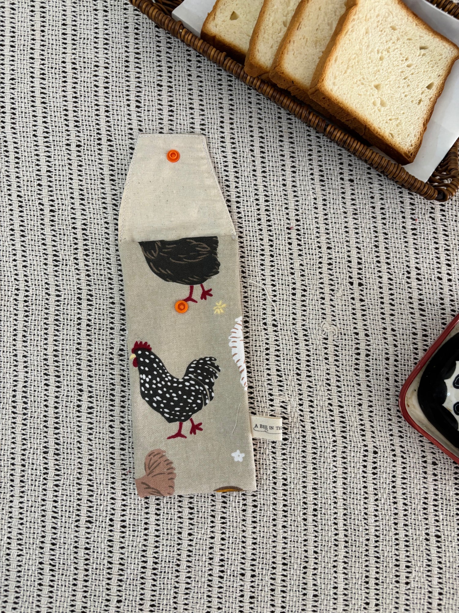 Fabric with chicken design on a textured surface with bread slices.