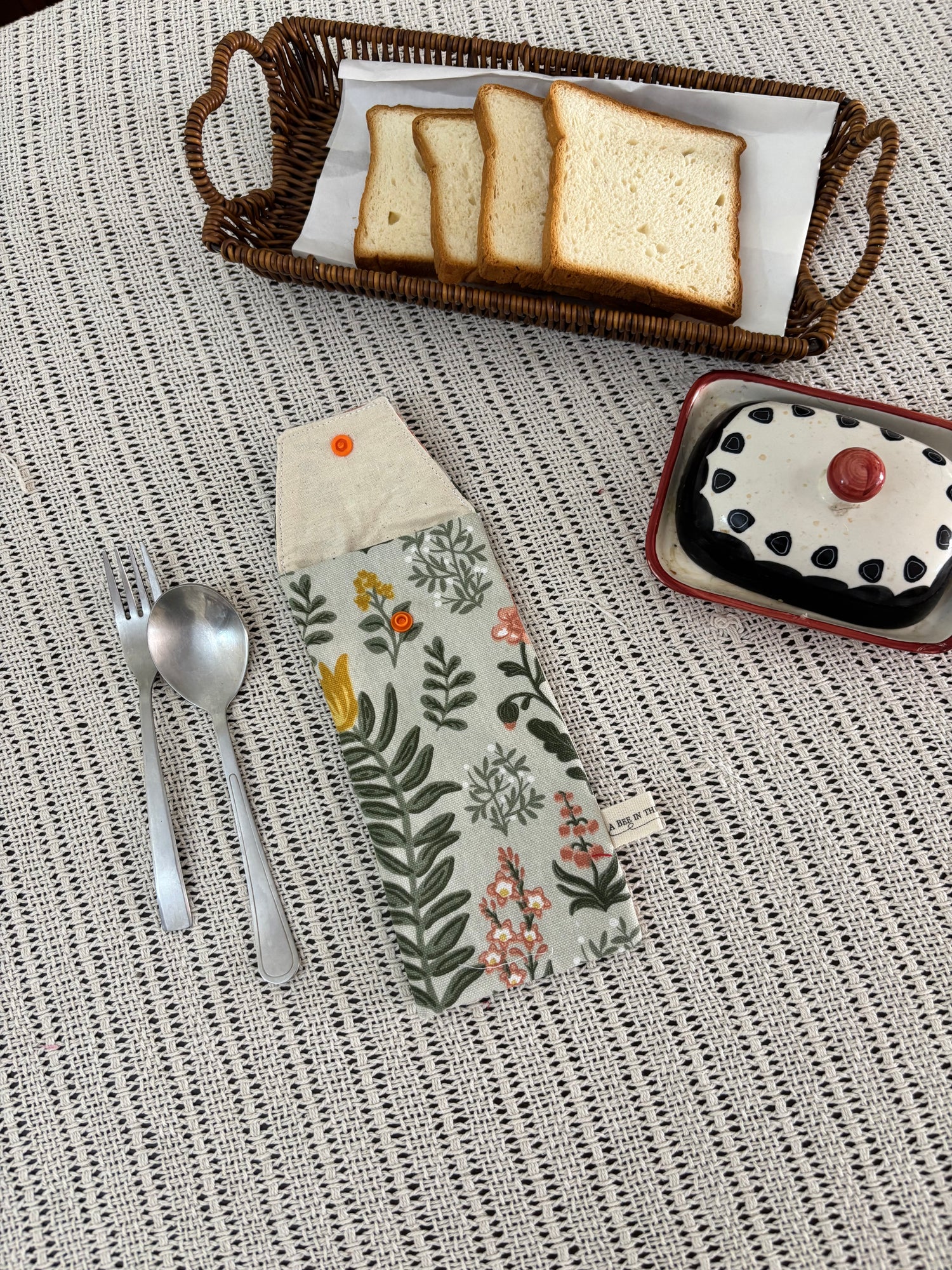 Bread slices in a basket, dessert in a bowl, and a floral-patterned knife on a textured surface.