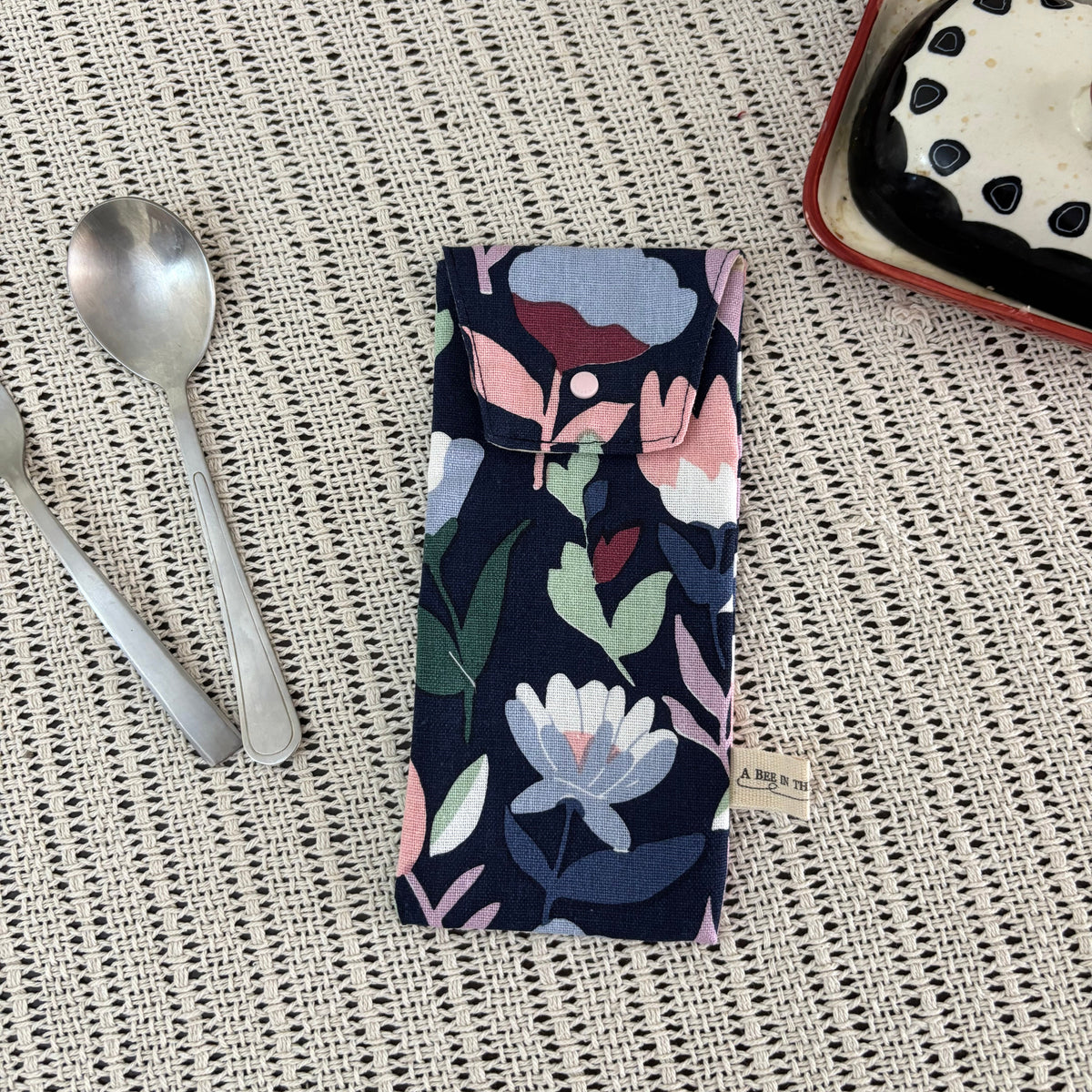 Floral-patterned fabric on a textured surface with a spoon and dessert in the background