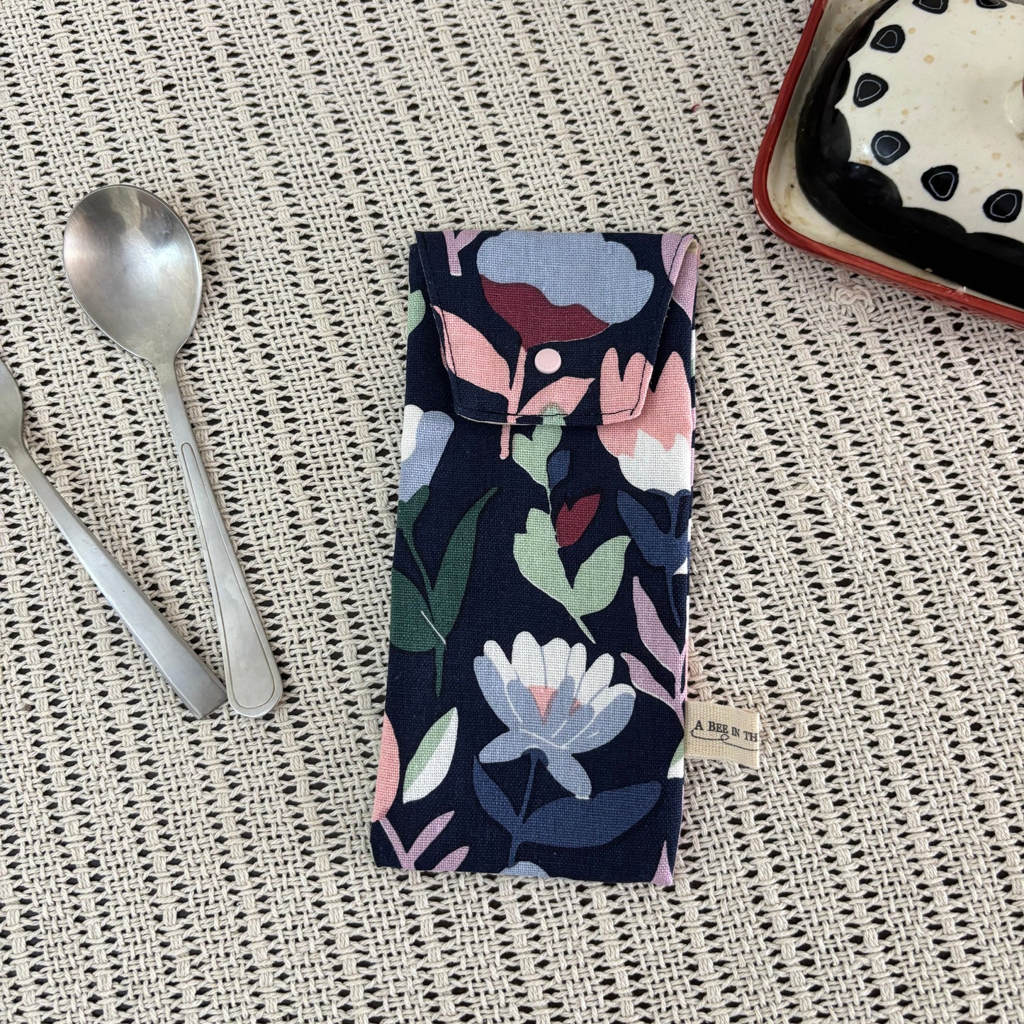 Floral-patterned fabric on a textured surface with a spoon and dessert in the background