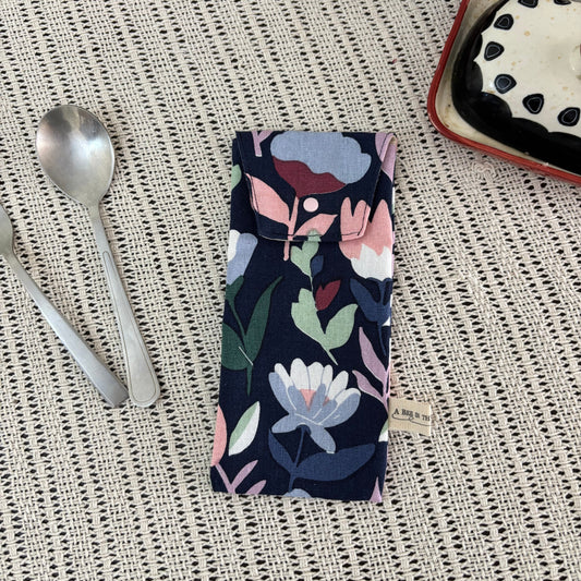 Floral-patterned fabric on a textured surface with a spoon and dessert in the background