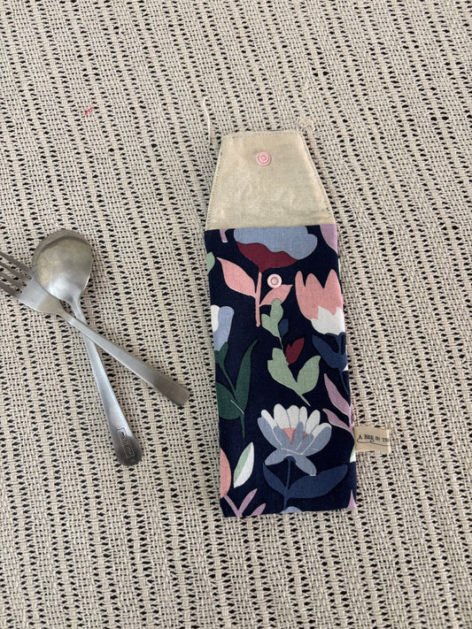 Floral-patterned pouch on a textured surface with silver spoons.