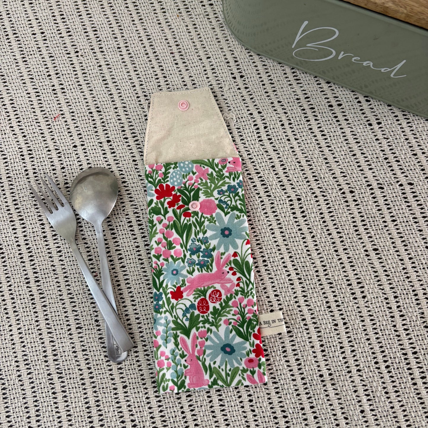 Floral-patterned bread box with a knife and fork on a textured surface