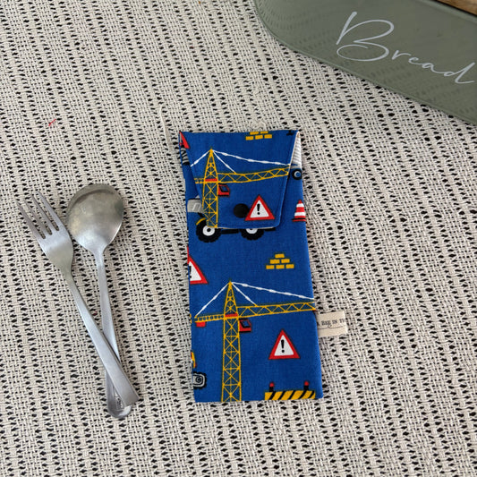 Blue fabric pouch with construction-themed design on a textured surface with cutlery.