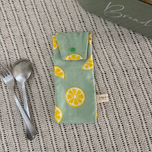 Fabric pouch with lemon pattern on a textured surface with cutlery