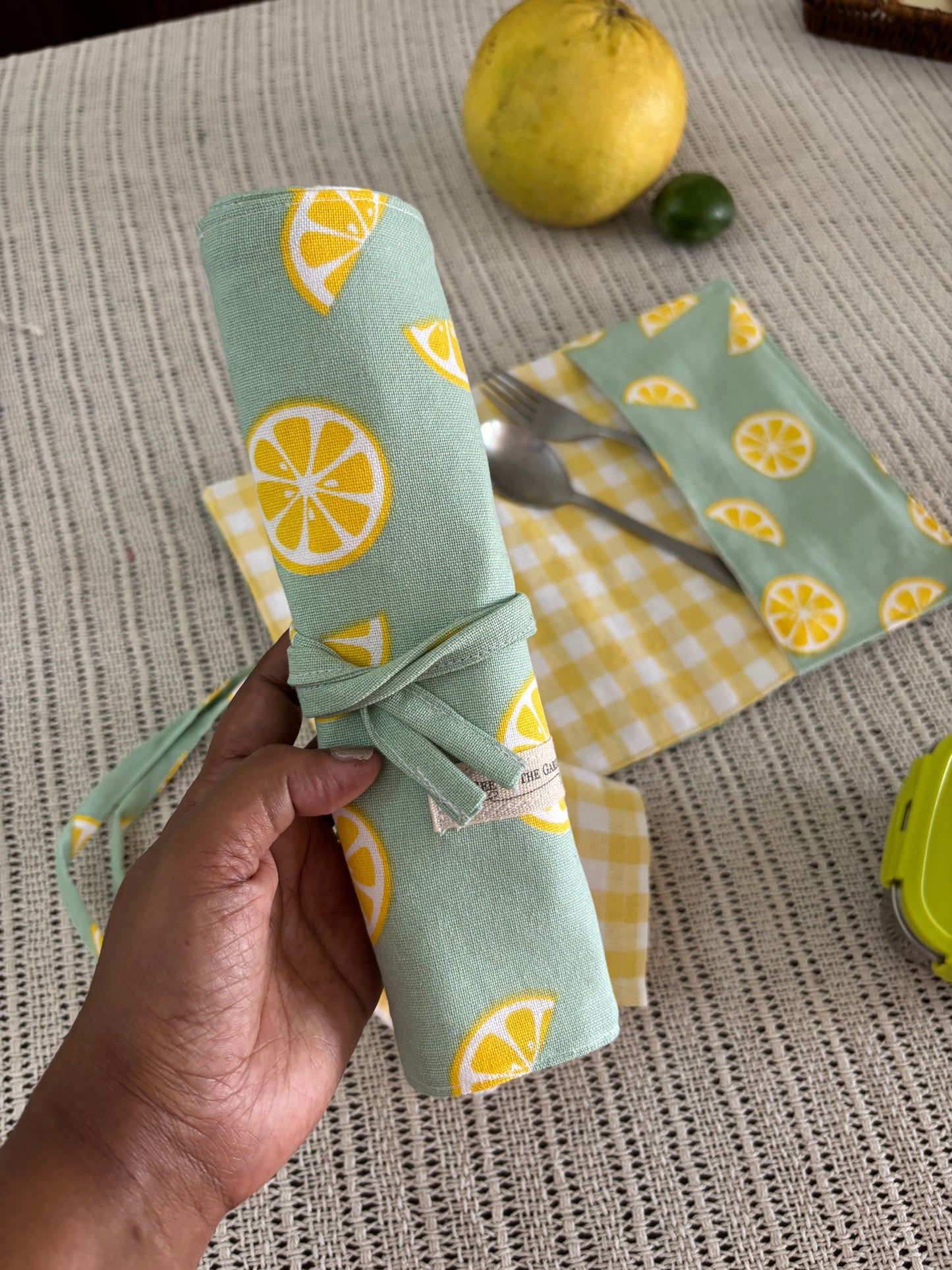 Hand holding a fabric-wrapped item with lemon pattern on a textured surface