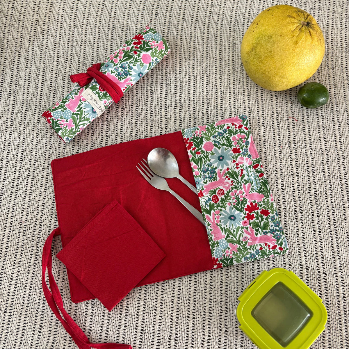 Red napkins with floral patterned cutlery holder on a textured surface
