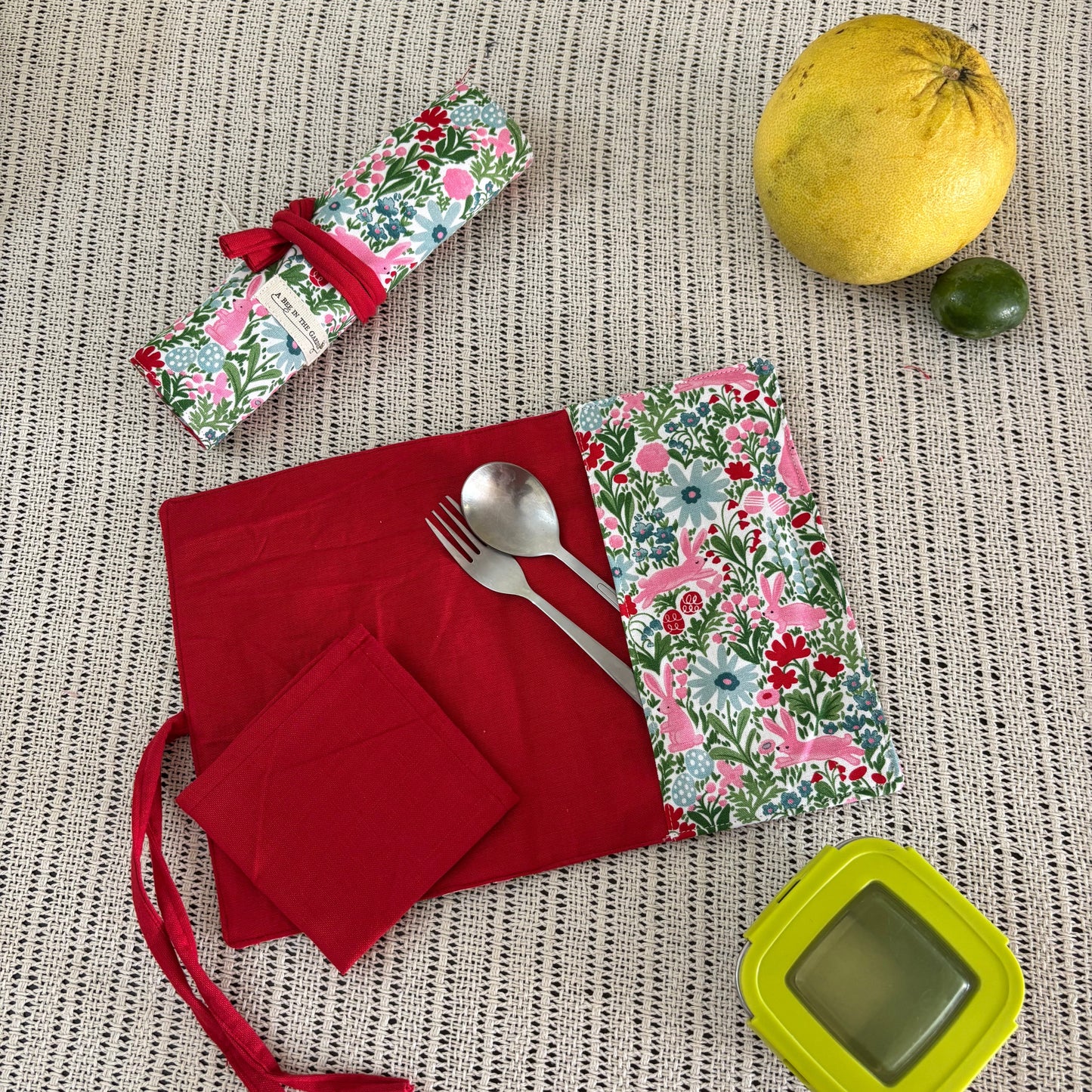 Red napkins with floral patterned cutlery holder on a textured surface