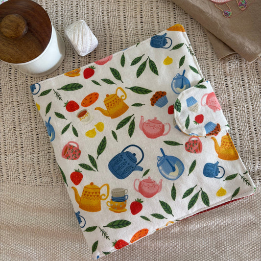 Baby bib with colorful teapot design on a textured surface