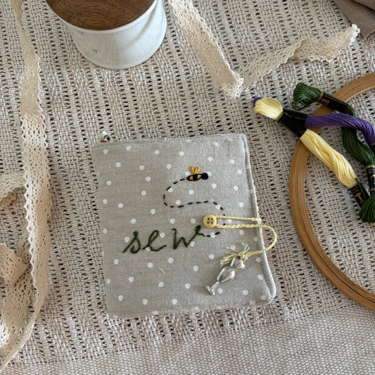 Small needlecase with 'sew' text on a textured fabric background