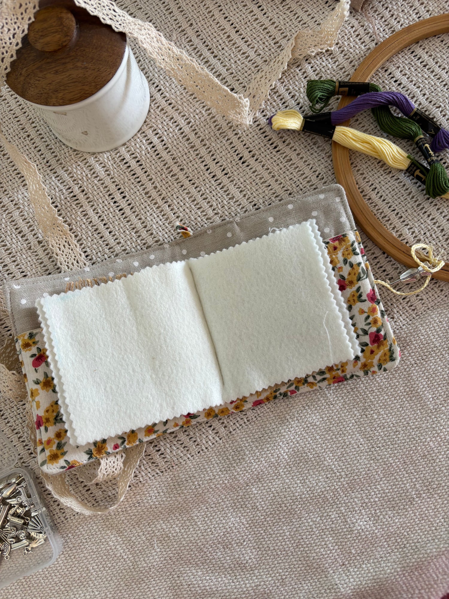 Floral embroidery hoop with fabric swatches on a textured surface