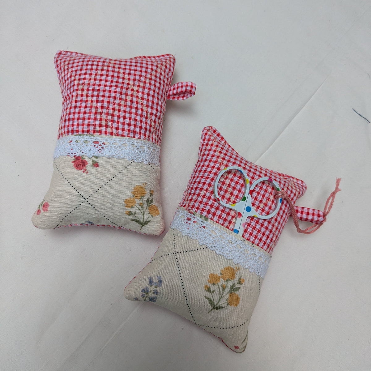 Two small fabric pincushions with floral patterns on a white surface