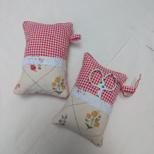 Two small fabric pincushions with floral patterns on a white surface