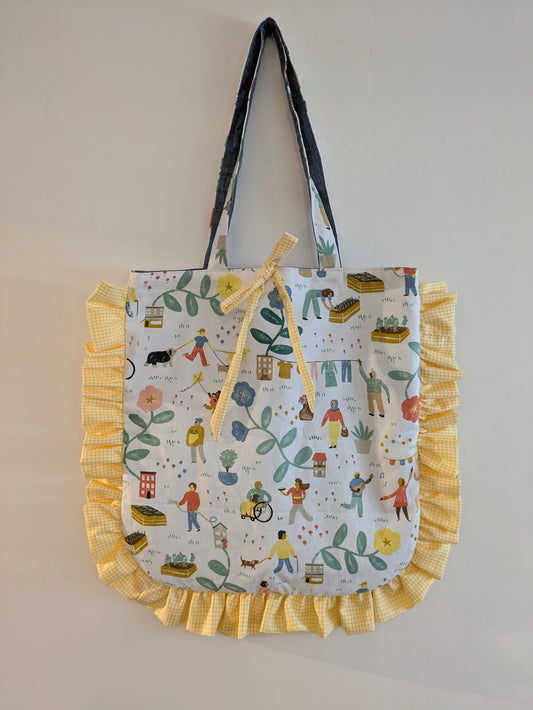 Tote bag with colorful pattern and yellow ruffles on a plain background