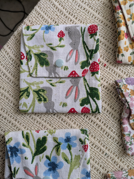 Fabric pouches with floral and animal patterns on a textured surface