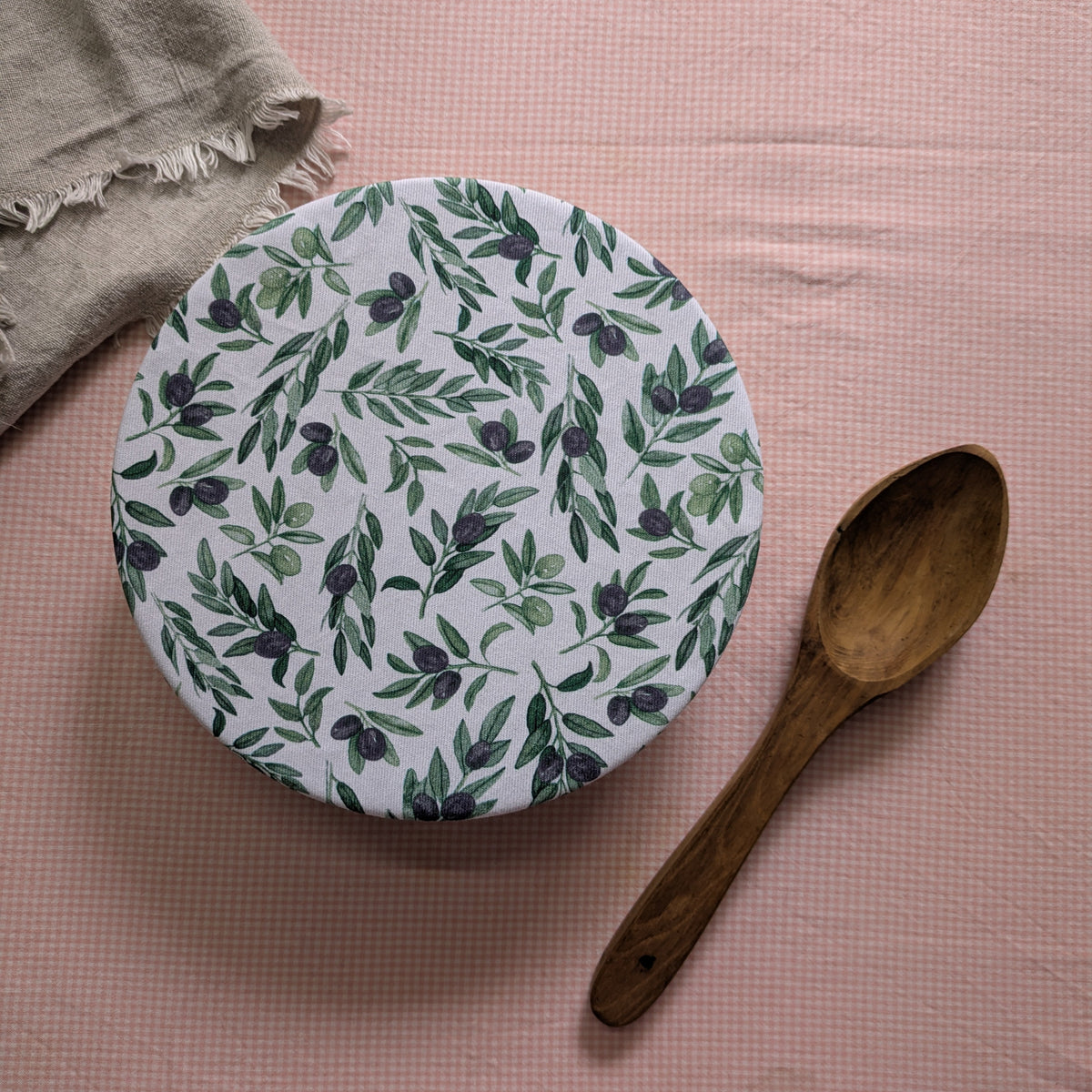 fabric bow lcover  used to cover a salad bowl , alongside an earthy wooden sppon