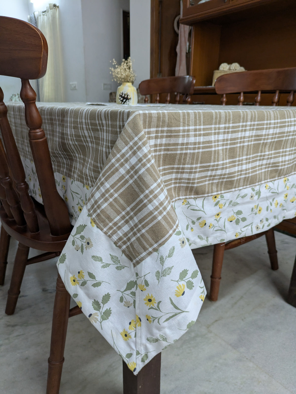 Dining table with a checkered and floral-patterned tablecloth in a home setting.