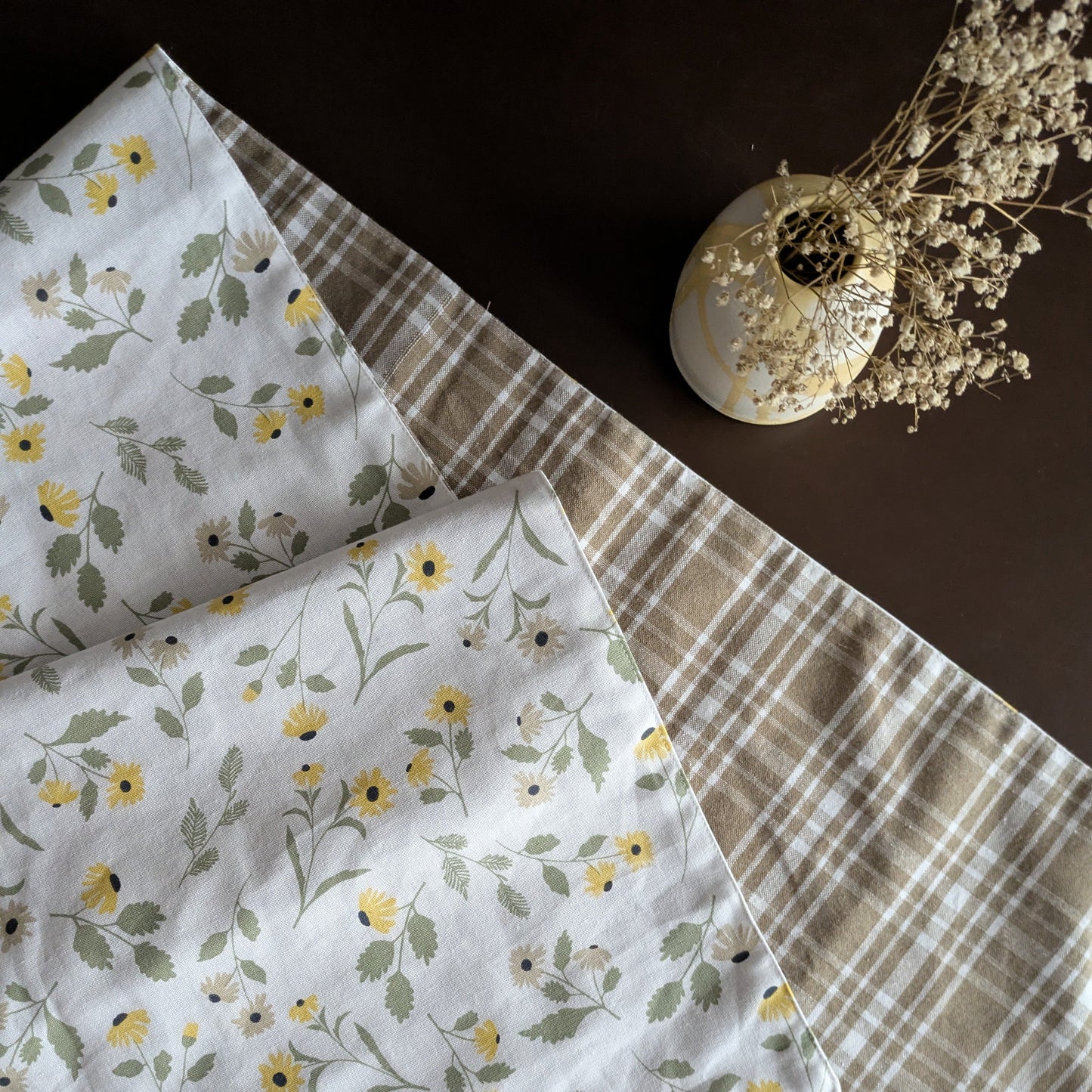 Floral patterned fabric with a plaid fabric on a dark surface.