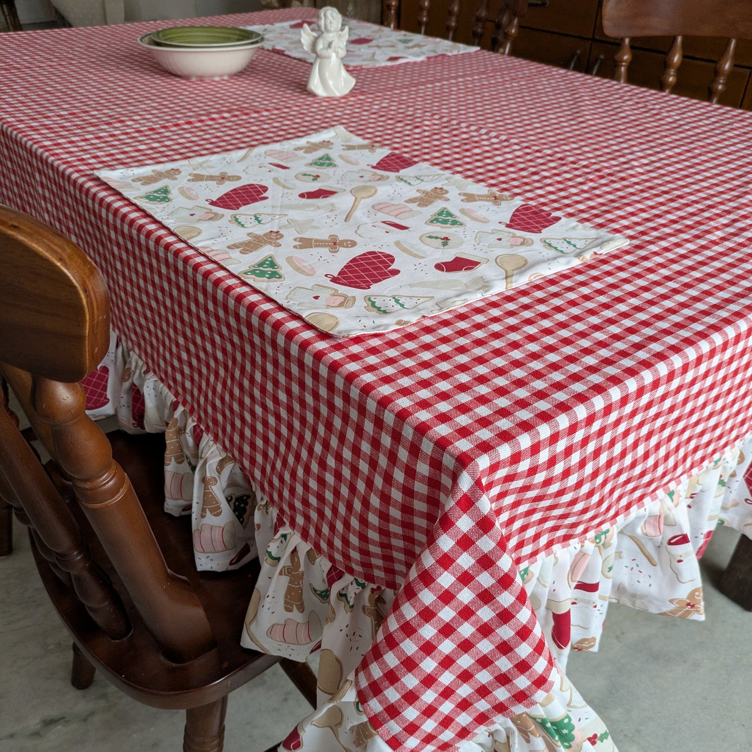 Tablecloth with red checkered pattern and gingerbread design on a wooden table.