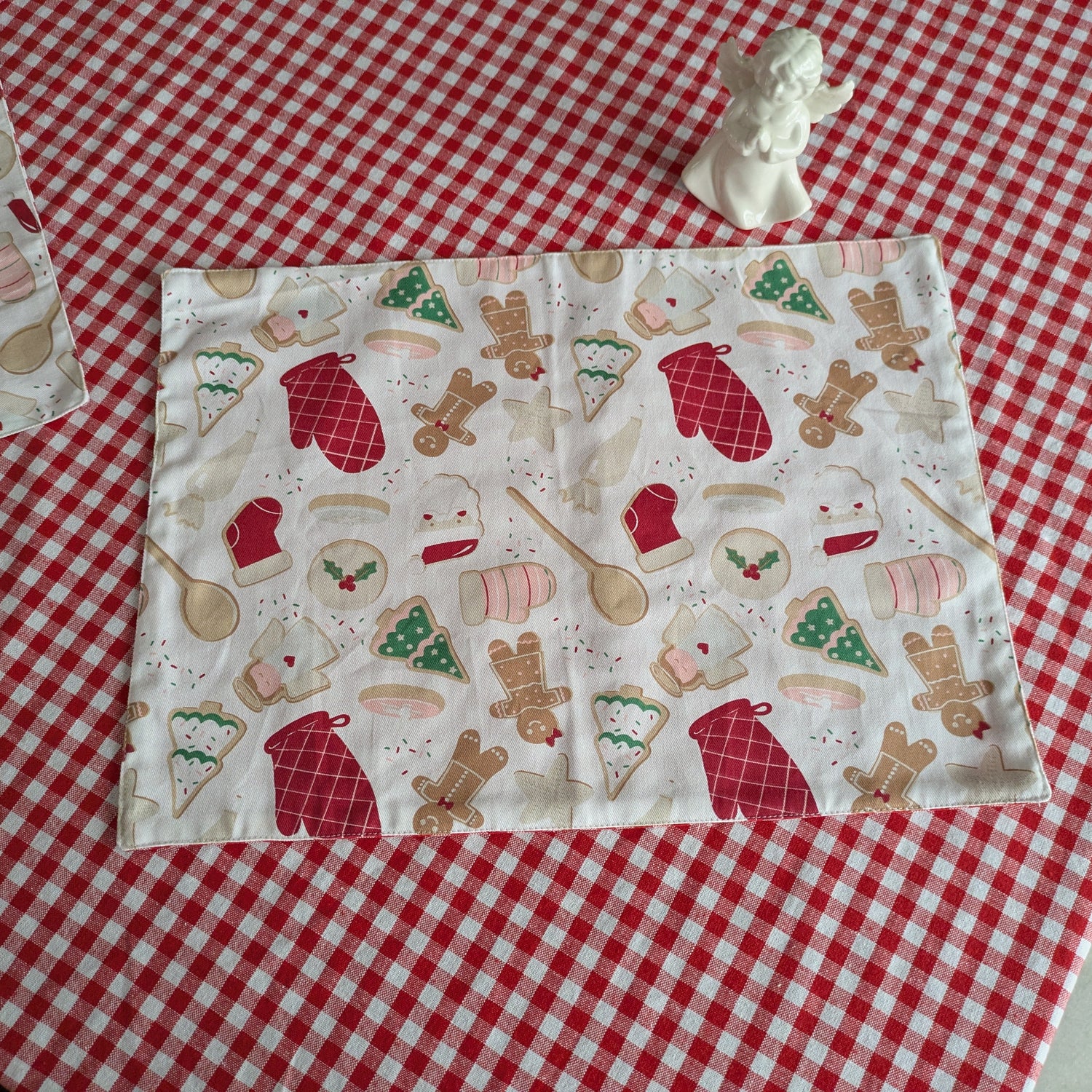 Fabric with Christmas-themed pattern table mat on a red and white checkered tablecloth
