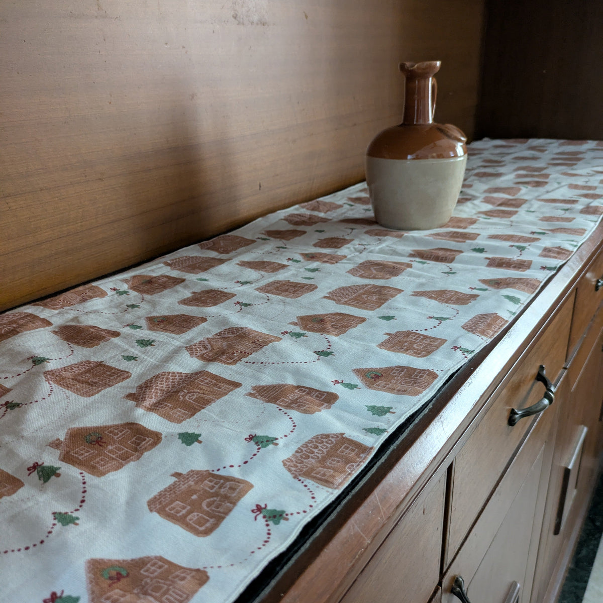 Cabinets with a decorative table runner featuring gingerbread houses.