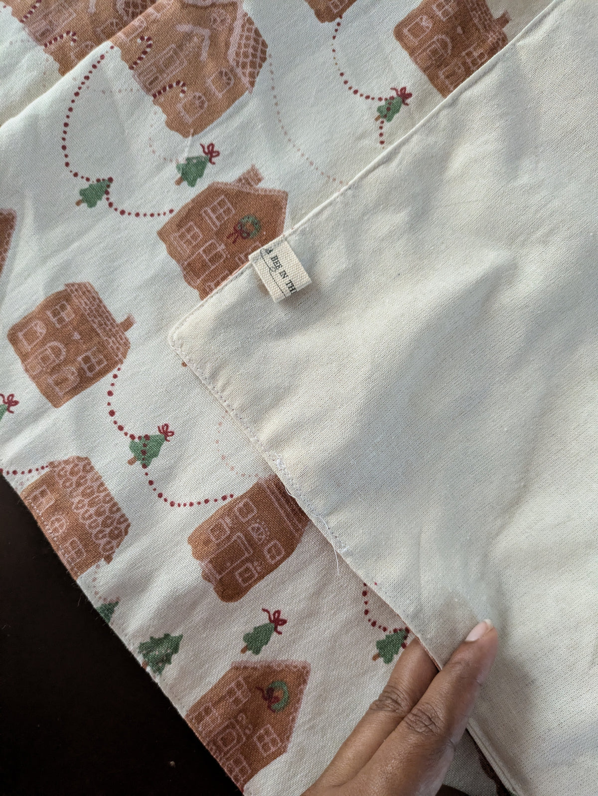 Fabric with gingerbread house pattern held by a hand