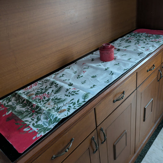 Wooden cabinet with a floral table runner and red container on top