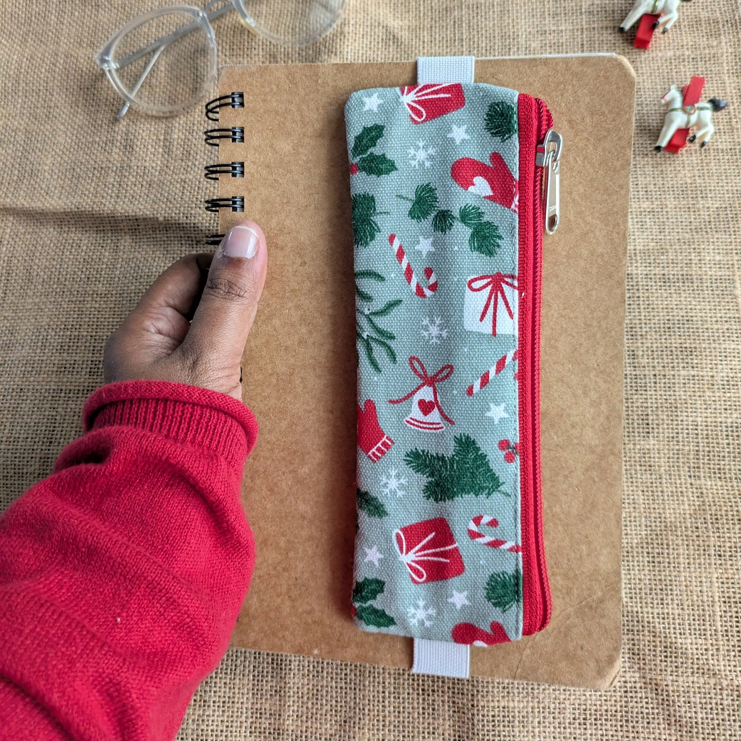 Pouch with Christmas pattern held by a hand on a textured surface