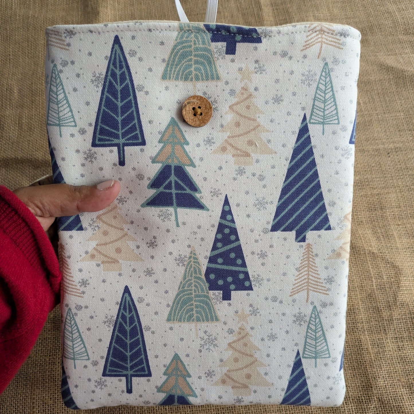 Fabric pouch with tree pattern held by a person on a textured surface